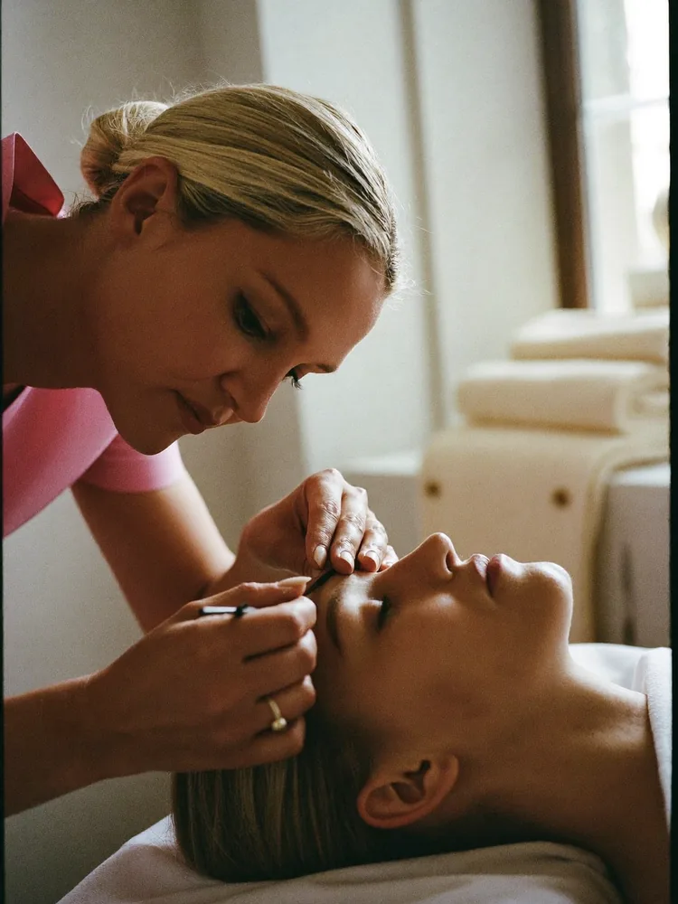 Therapist shaping a client's eyebrow, close and precise