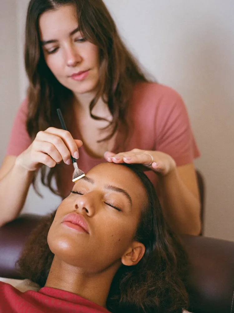 Therapist brushing a client's brows through with a spoolie