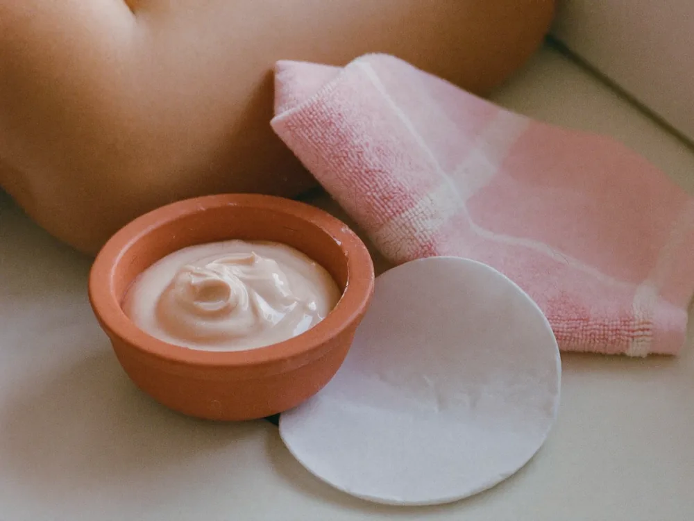 A bowl of cream and a folded towel on a treatment trolley