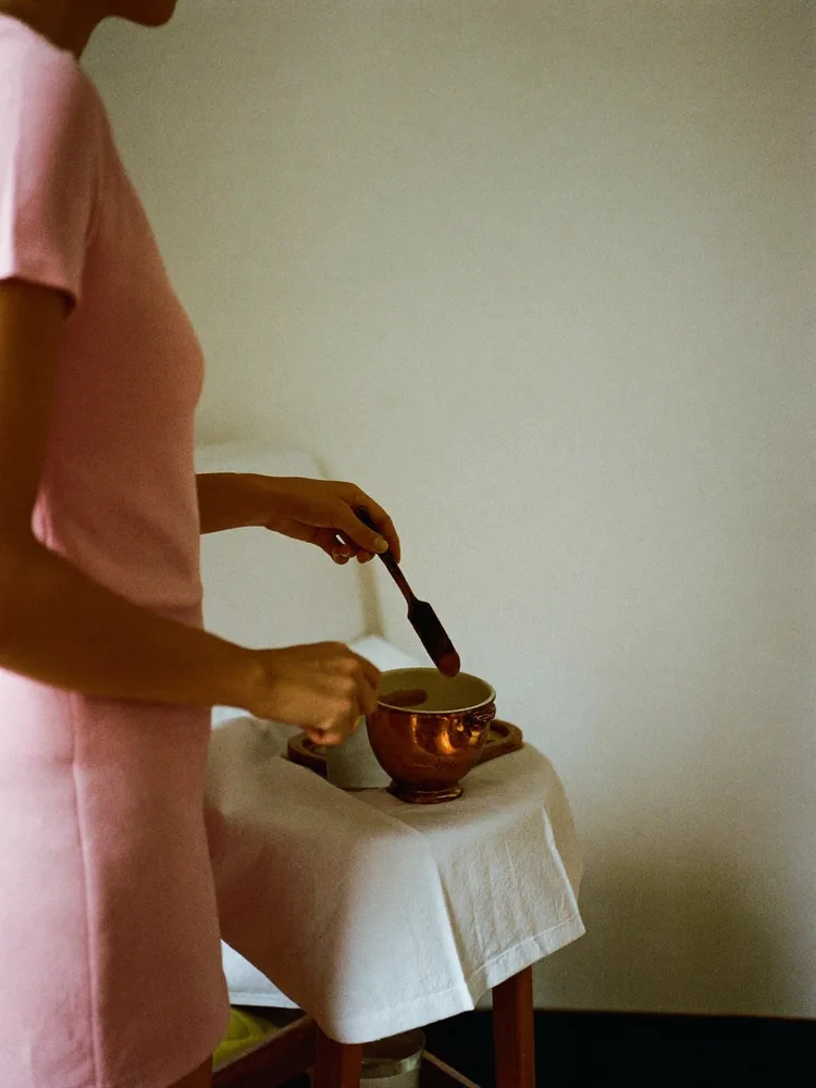 Therapist warming wax in a small pot beside a treatment couch